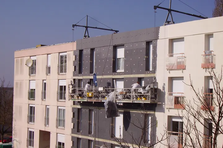 Fachada con placas de aislamiento térmico colocadas y plataforma suspendida de trabajo