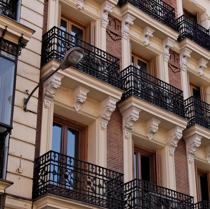 Fachada de un edificio de viviendas madrileño con balcones de forja y ménsulas decoradas